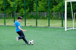 der junge spielt fußball im hof, auf dem rasen. Kind tritt den Ball foto