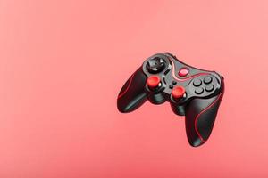 Ein schwarzer Joystick-Gamecontroller schwebt isoliert auf einem rosa Hintergrund. foto