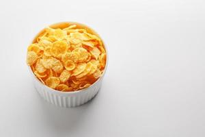 weiße Tasse mit goldenen Cornflakes isoliert auf weißem Hintergrund. Sicht von oben. leckeres und gesundes Frühstück foto
