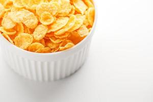 weiße Tasse mit goldenen Cornflakes isoliert auf weißem Hintergrund. Sicht von oben. leckeres und gesundes Frühstück foto
