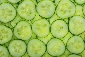 Scheiben grüner frischer Gurke mit Hintergrundbeleuchtung als struktureller Hintergrund foto