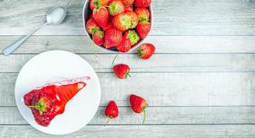 Draufsicht auf frische Erdbeerkuchenscheiben auf einem Teller und frische rote Erdbeeren auf einem blauen alten Holzhintergrund foto