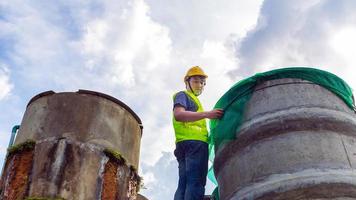 ingenieur, der die qualität des wassers kontrolliert, steht auf den riskanten treppen an hohen orten, die industrielle wasserreinigungs- oder filtrationsanlagen betreiben, alte zementtanks, um wasser in der wasserfabrik zu halten foto