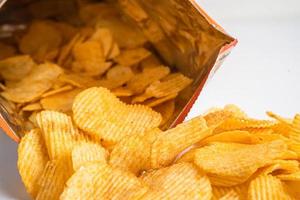 Kartoffelchips, leckeres Grillgewürz würzig für Crips, dünne Scheiben frittierter Snack Fast Food im offenen Beutel. foto