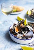 Miesmuscheln in cremiger Weißweinsauce, serviert mit Limette und Brot. Muscheln in Wein, Lauch und Blauschimmelkäse schmoren. Meeresfrüchte. foto