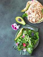 Hausgemachtes Chapati- oder Roti-Fladenbrot mit grüner Salatmischung, Avocado und Sprossen, Betonhintergrund. frisch gebackenes indisches Fladenbrot. foto