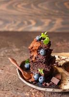 Zartbitterschokoladen-Brownie mit Blaubeere, Minze, Schokoladensauce und Bitterschokoladenstückchen. leckeres hausgemachtes Fudge und zähes Dessert mit schmelzender Schokolade. foto