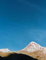 berg kazbek in den strahlen der morgensonne, vertikaler rahmen, früher herbst in den bergen. Hoher Kaukasus, Georgien foto