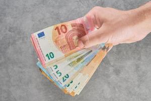 Die Hand eines Mannes, einer kaukasischen ethnischen Gruppe, hält Euro-Banknoten, Draufsicht, Gelddarlehen. das konzept eines banners, layouts oder hintergrunds für nachrichten, zahlung von stromrechnungen foto