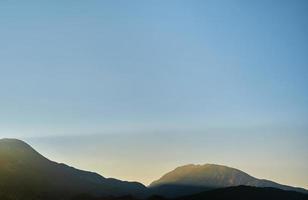 die sonne bei sonnenaufgang beleuchtet die berge, früher morgen in den bergen an der mittelmeerküste, urlaubswerbeidee, hintergrund für einen splashscreen mit freiem platz foto