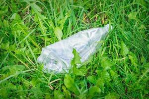 Zerknitterte Plastikflasche, die im grünen Gras liegt foto