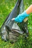 Kind nimmt Plastikmüll aus dem Gras foto