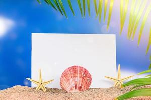 Seestern und Muschel auf Sand mit Blatt Papier für Text, Palmzweige an der Seite. sonniger Tag. das konzept von strand, urlaub, reise. Platz kopieren foto