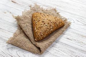 frisch gebackenes Brot oder Brötchen mit Sesam und Sonnenblumenkernen auf Holztisch foto