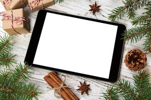 digitales tablet-modell mit rustikalen weihnachtlichen hölzernen hintergrunddekorationen für app-präsentation. draufsicht mit kopierraum foto