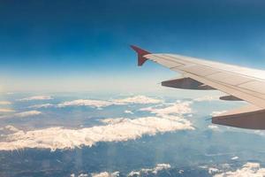 Blick aus dem Fenster des Flugzeugs, das über die Berge fliegt foto