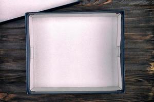 offene weiße Pappschachtel auf einem dunklen Tisch, Holzhintergrund. vintage, getönte draufsicht foto