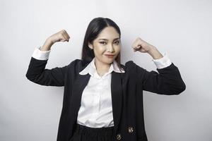 Aufgeregte asiatische Geschäftsfrau, die einen schwarzen Anzug trägt und eine starke Geste zeigt, indem sie ihre Arme und Muskeln stolz lächelt foto