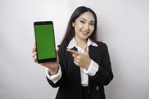 Eine glückliche junge Geschäftsfrau trägt einen schwarzen Anzug und zeigt Kopienraum auf ihrem Telefon, das durch weißen Hintergrund isoliert ist foto