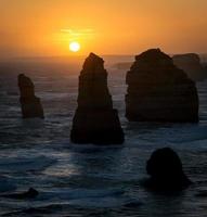 Silhouetten von Felsen im Ozean bei Sonnenuntergang foto