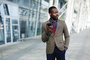 stilvoller Afroamerikaner schwarzer Geschäftsmann arbeitet auf seinem Smartphone