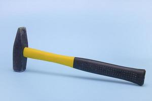 Mallet, Hammer mit schwarz-gelbem Griff auf hellblauem Hintergrund, das Konzept von Konstruktion, Werkzeug, Reparatur, Brutalität foto