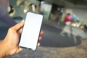 Hand des jungen Mannes mit Smartphone mit grünem Bildschirm im Café foto