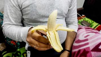 junger asiatischer mann im weißen t-shirt, der hand in hand banane schält foto