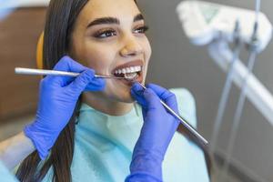 Frau schaut im Zahnarztstuhl in den Spiegel. Zahnfarbe des Patienten mit Mustern für die Bleichbehandlung. Mundhygiene angesehen. Frau beim Zahnarzt. foto