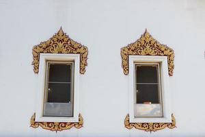Goldener und roter Farbrahmen aus weiß gestrichenen Holzfenstern auf weiß gestrichener Zementwand im alten einheimischen thailändischen Baustil im Tempel in Bangkok, thailand. foto