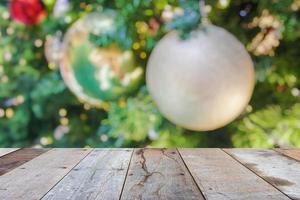 leere hölzerne tischplatte mit unscharfem weihnachtsbaum mit bokeh hellem hintergrund foto