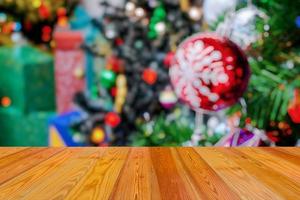 leere hölzerne tischplatte mit unscharfem weihnachtsbaum mit bokeh hellem hintergrund foto