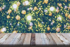 leere hölzerne tischplatte mit unscharfem weihnachtsbaum mit bokeh hellem hintergrund foto