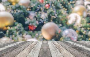leere hölzerne tischplatte mit unscharfem weihnachtsbaum mit bokeh hellem hintergrund foto