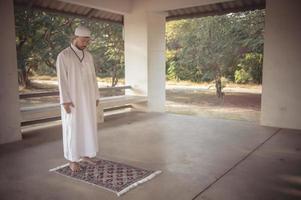 junger asiatischer muslimischer mann, der bei sonnenuntergang betet, ramadan-festkonzept foto