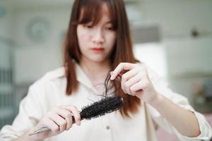 asiatische Frau hat Probleme mit langem Haarausfall an der Kammbürste. foto