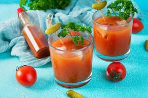 Alkoholcocktail Bloody Mary auf blauem Hintergrund. Klassischer Cocktail mit Tomatensaft und Wodka foto