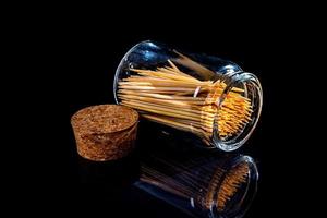Bambus-Zahnstocher aus Holz im Glas, Weinglas. im Eimer. Zahnstocher auf schwarzem Hintergrund. Vorderansicht Zahnstocher, aus der Hand gefallen, Platz für Text, foto