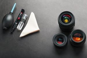 Werkzeuge zum Reinigen der Kamera mit Objektiven auf einem dunklen strukturierten Hintergrund. foto