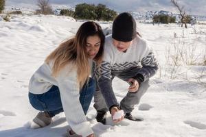 mutter und sohn spielen mit schneebällen auf einem schneebedeckten feld foto