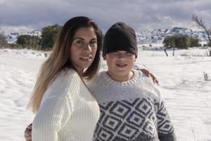 Porträt von Mutter und Kind, die auf einem schneebedeckten Feld in die Kamera blicken foto