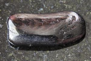 getrommelter Hypersthene-Edelstein auf dunklem Hintergrund foto