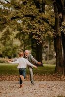 Großvater verbringt am Herbsttag Zeit mit seiner Enkelin im Park foto