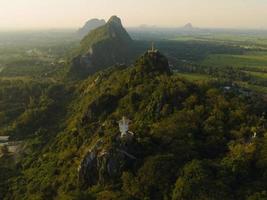 eine luftaufnahme von christus dem erlöser und buddha auf dem berg steht prominent in hup pha sawan in ratchaburi in der nähe von bangkok, thailand foto