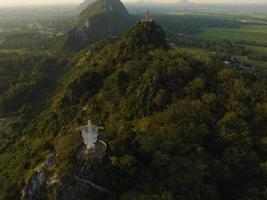 eine luftaufnahme von christus dem erlöser und buddha auf dem berg steht prominent in hup pha sawan in ratchaburi in der nähe von bangkok, thailand foto