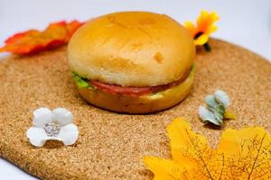 selektiver fokus des hamburgers auf holztablett mit blumendekoration. foto