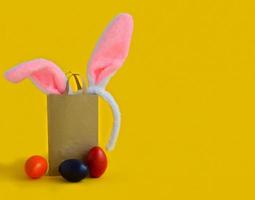 Banner auf gelbem Hintergrund. das konzept des online-shoppings für ostern, online-käufe und -verkäufe für den urlaub. geschenktüte mit hasenohren osterfarbene eier symbole, traditionen foto