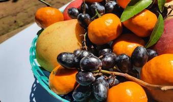 Nahaufnahme, tropische Früchte von Orangen, Trauben und Birnen im grünen Korb auf weißem Hintergrund 02 foto