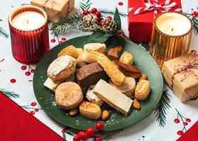 Draufsicht auf Nougat-Weihnachtsbonbon, Mantecados und Polvorones mit Weihnachtsschmuck auf einem Teller. auswahl an weihnachtssüßigkeiten, die typisch für spanien sind foto
