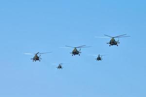 Militärhubschrauber, die am blauen Himmel fliegen und Demonstrationsflüge, Kunstflugstaffeln, Flugschau durchführen foto